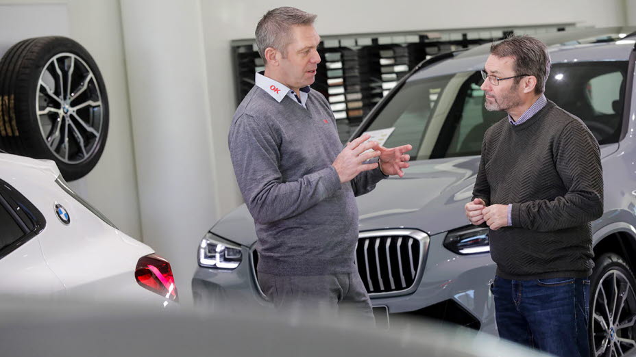 To mænd foran bil - NCG har fået ladeløsning fra OK