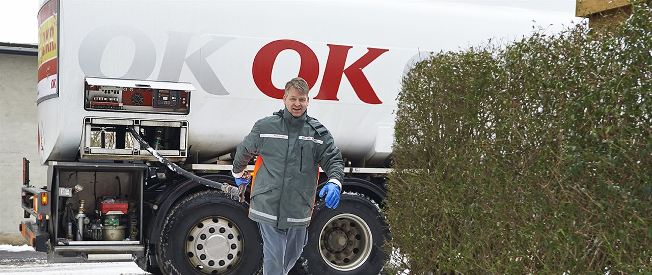 En af OK's tankvognschauffører på vej ind til hus med olieslange i hånden