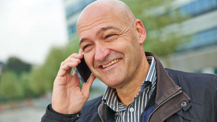 Smilende mand holder mobiltelefon op til øret