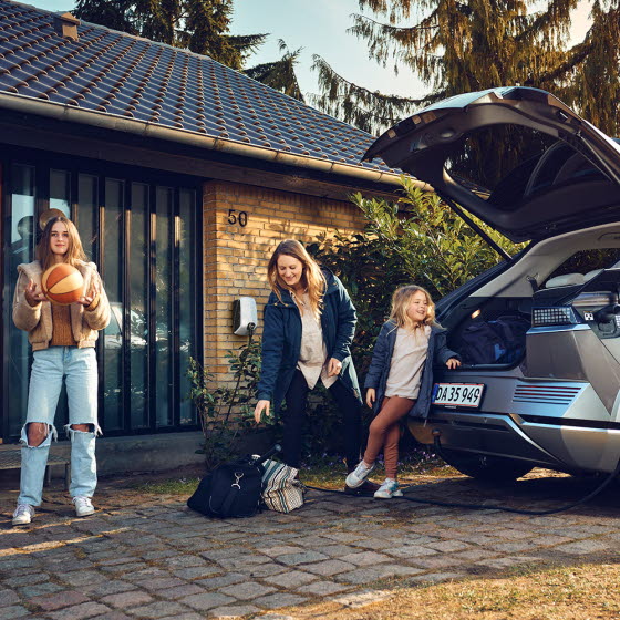 Familie ved elbil med hjemmelader