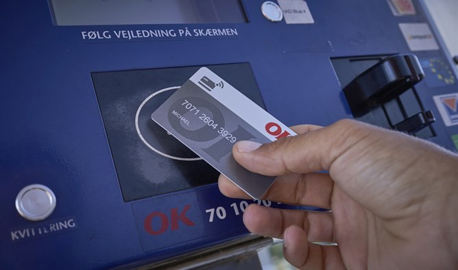 Hånd med OK Erhvervskort ved en betalingsautomat