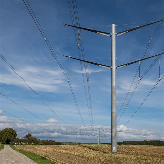 Højspændingsmast på kornmark med blå himmel
