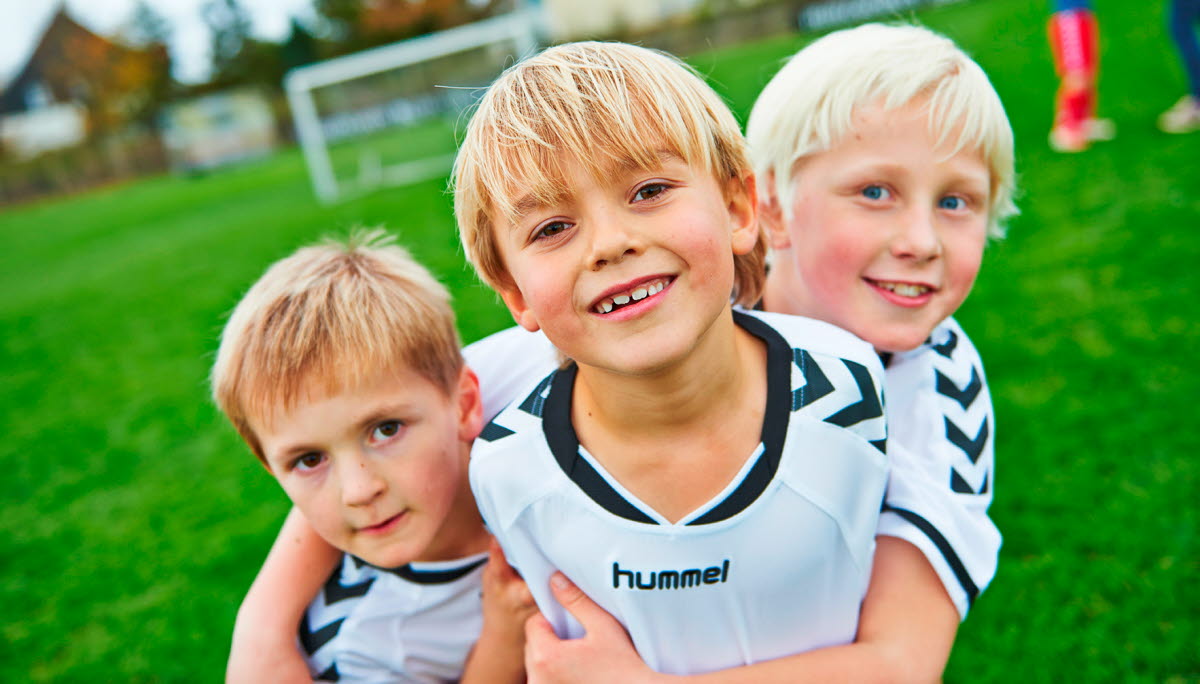 Tre fodbolddrenge iført OK fodboldtrøjer