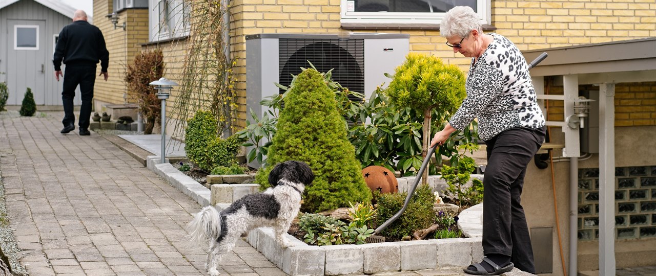 Dame ordner sin have med sin hund ved siden af sig