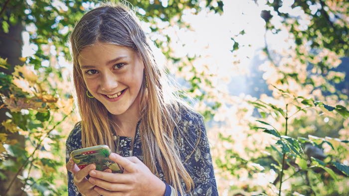 Pige i skoven med sin mobiltelefon