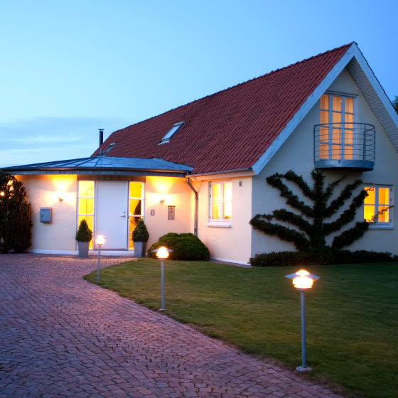 Hvid villa med tændte lamper udendørs og inde