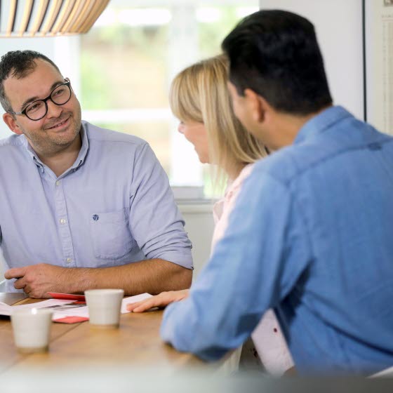 Mand og par drikker kaffe ved bord varmeumper rådgivning