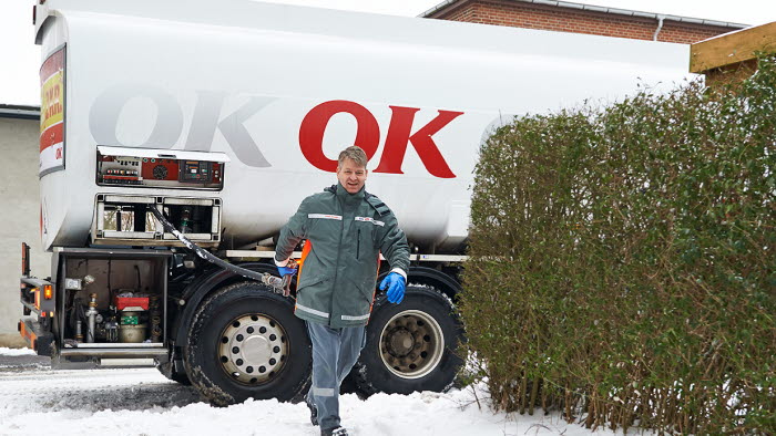 En af OK's tankvognschauffører på vej ind til hus med olieslange i hånden