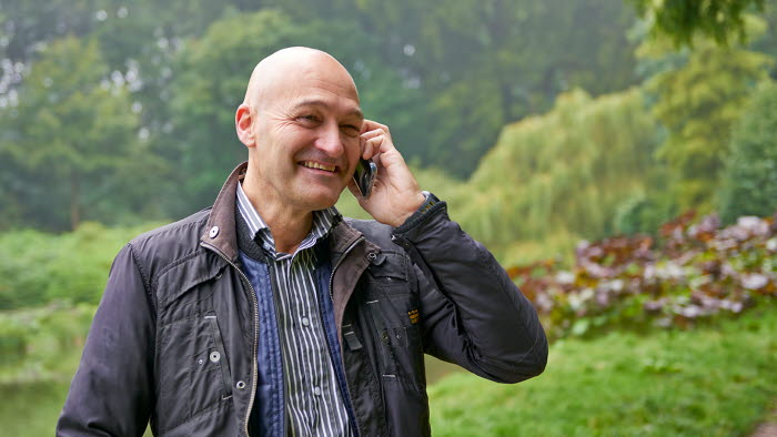 Mand taler i mobiltelefon med grønt område i baggrunden