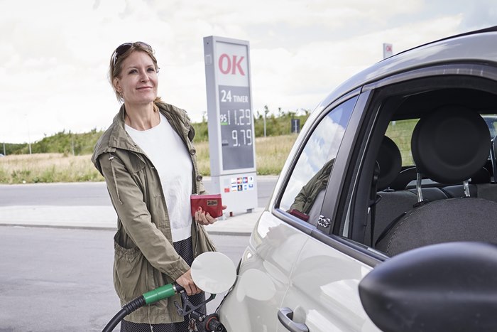 Kvinde i færd med at tanke bil på OK-tankstation