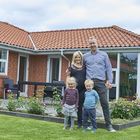 Familie samlet foran et rødt murstenshus