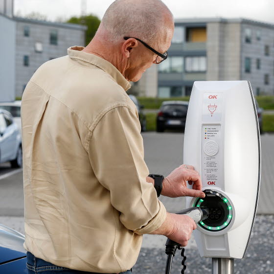 Mand ved ladestander med ladestik i hånden