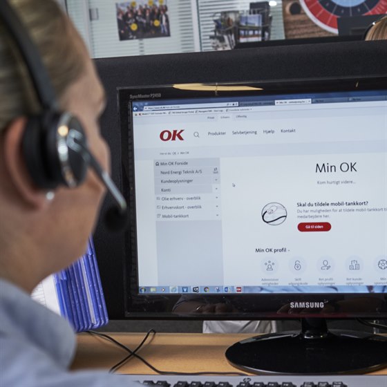 Kvinde sidder ved computerskærm med OK's selvbetjening Min OK foran sig