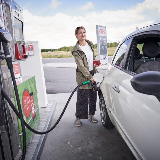 Kvinde i færd med at tanke bil på OK-tankstation