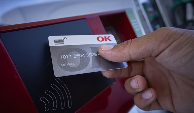 Hånd med et OK Erhvervskort ved kontaktfri betalingsautomat