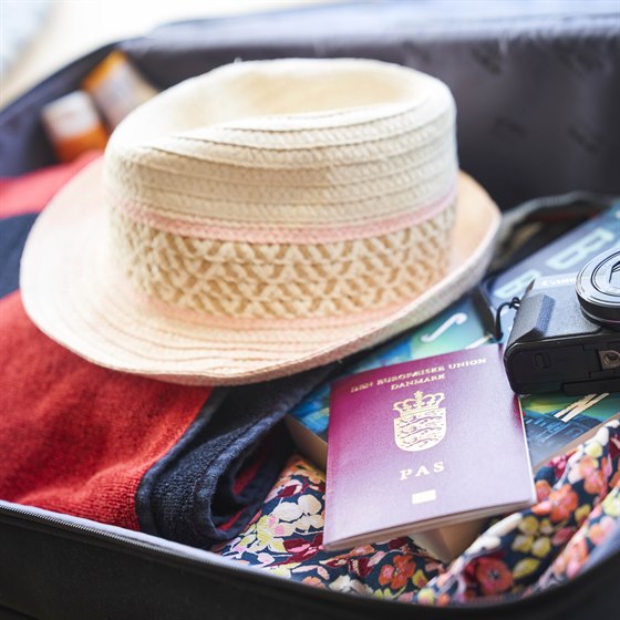 Kuffert pakket med tøj, stråhat, kamera og pas