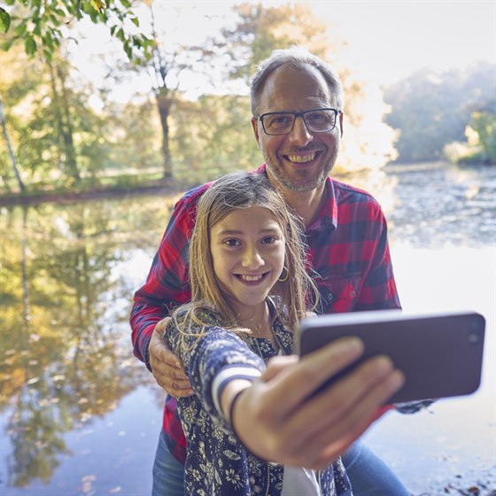Far og datter i skoven tager selfie med mobiltelefon