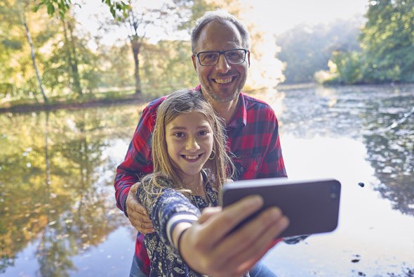 Far og datter i skoven tager selfie med mobiltelefon