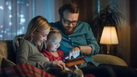 Familie sidder i sofa med tablet