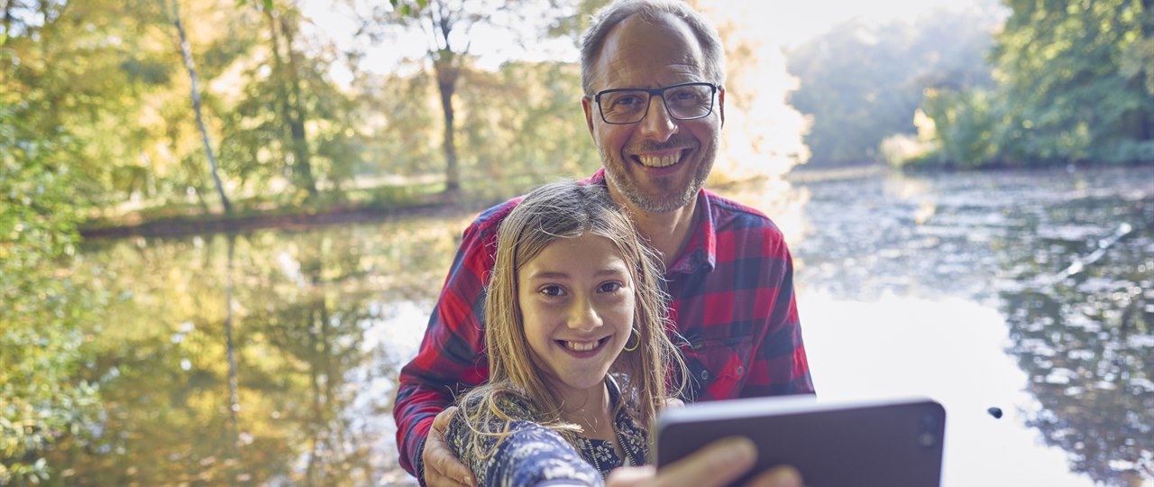 Far og datter i skoven tager selfie med mobiltelefon
